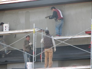 Four men on scaffolding applying Stucco to a Condo or Strata Property